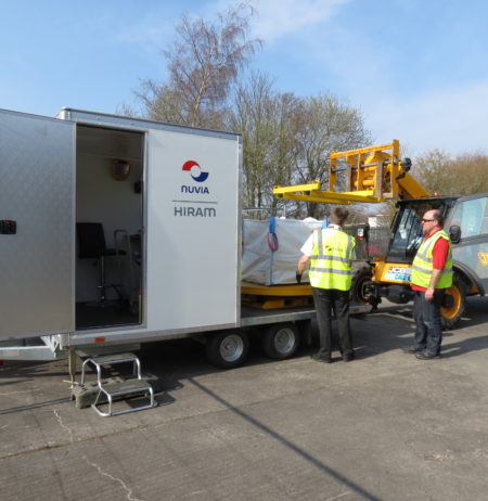 Two men working with a High Resolution Assay Monitor-trailer mounted system and a worksite vehicle