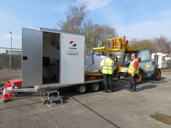 Two men working with a High Resolution Assay Monitor-trailer mounted system and a worksite vehicle