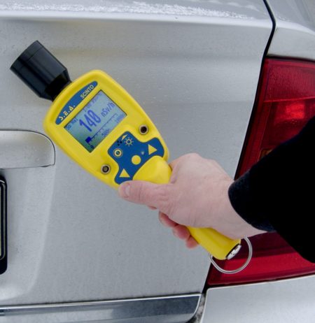 Someone using a high-sensitive gamma radiation monitor on a car