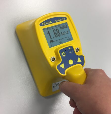Someone using a hand-held contamination monitor on a surface
