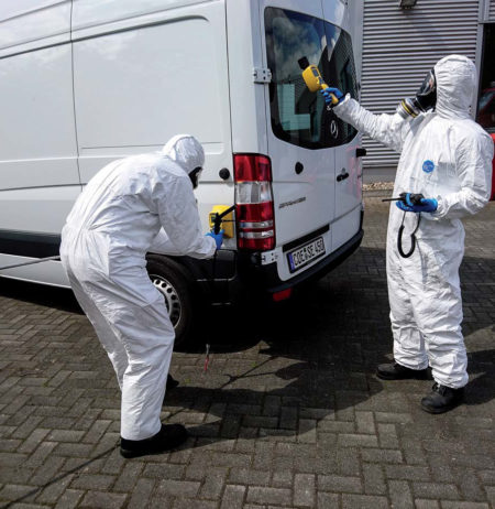 Two persons monitoring a vehicle for contamination by radiations