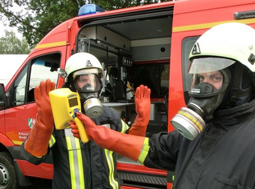 Fireman measuring another one's dose rate with a hand-held contamination monitor